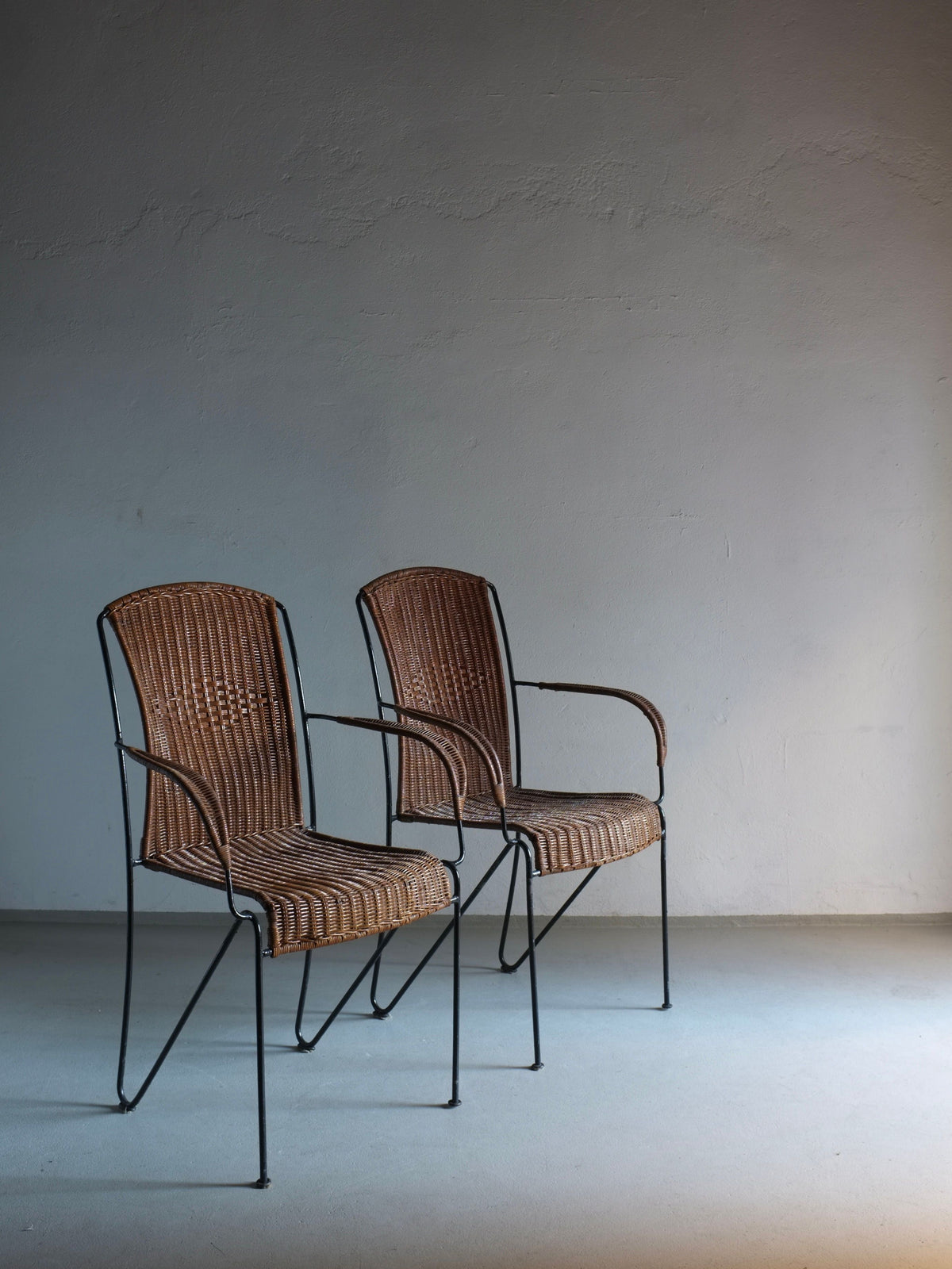 Two Frederick Weinberg wicker iron armchairs against minimal wall