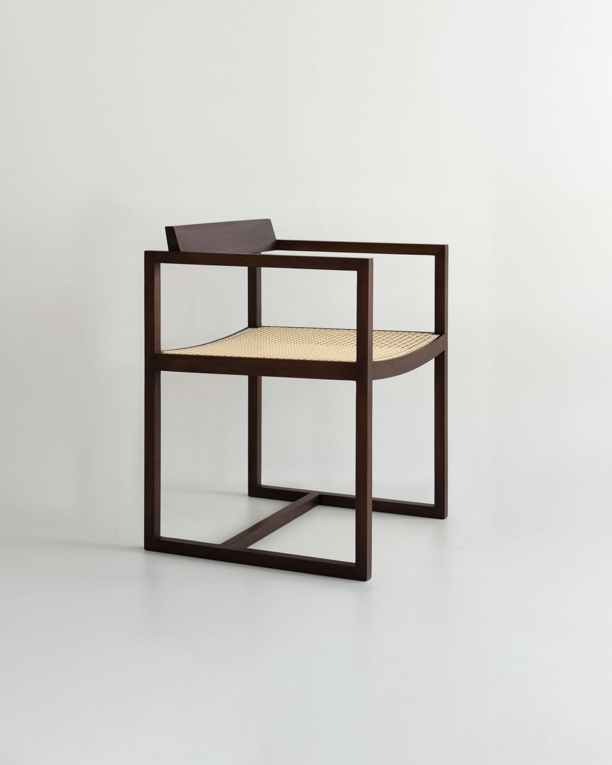 The "Amélia" Armchair by Andre Grippi features a minimalist design with a dark wooden frame, square armrests, and a woven straw seat, set against a plain light background.