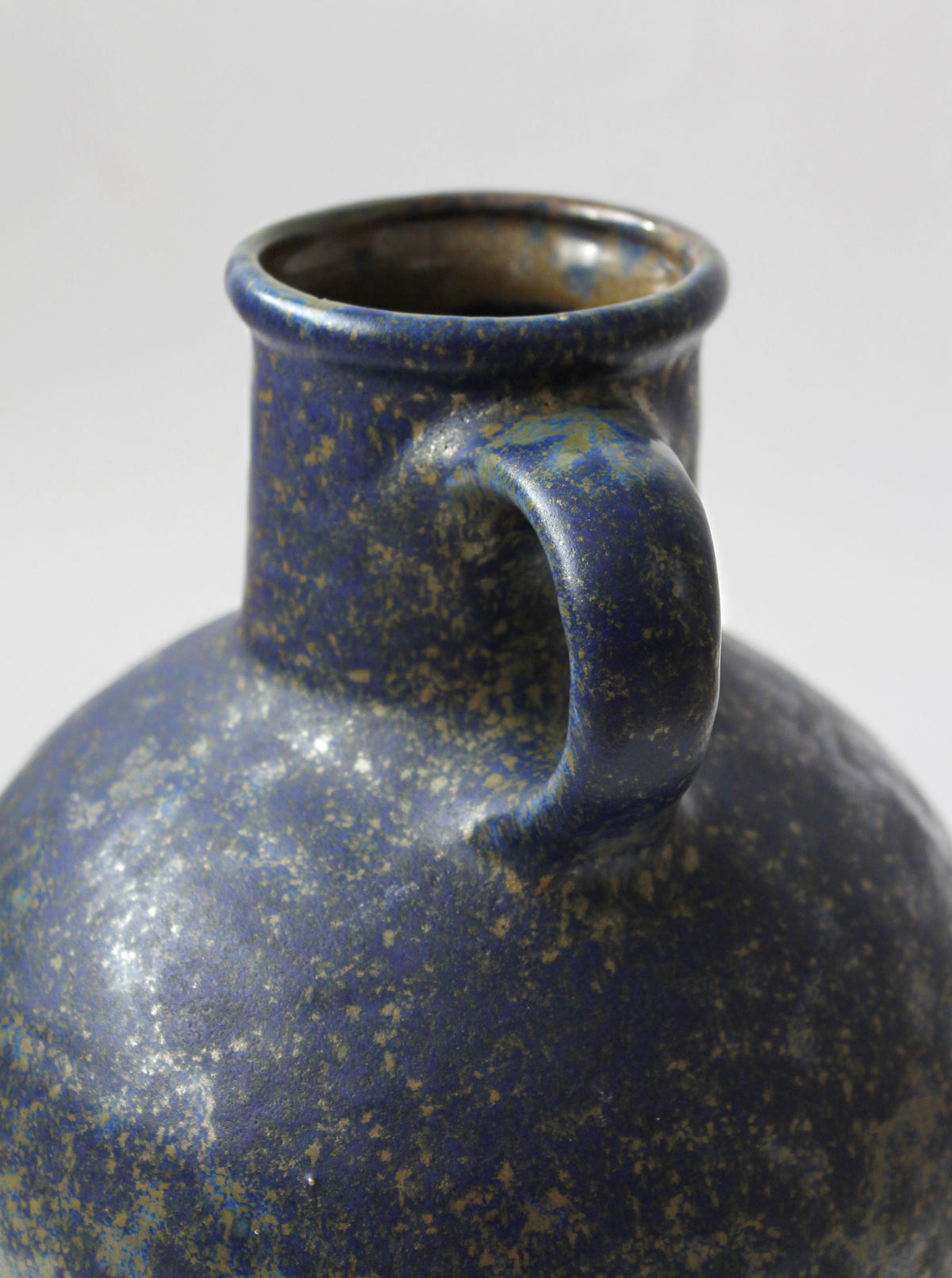 Close-up detail of blue speckled ceramic jug neck and handle