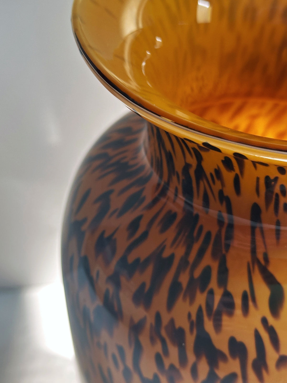 Close-up of the top of a 1980s Murano Vase Tortoise pattern by Dodo Vintage. The amber glass and tortoise-like design shine under bright light, highlighting its glossy surface and fine Italian craftsmanship.