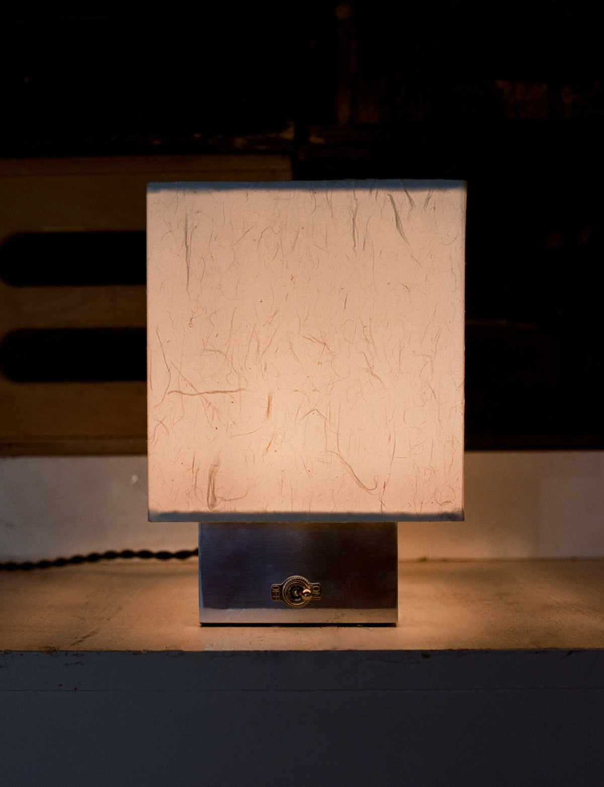 Modern cubic table lamp with textured beige shade on dark base