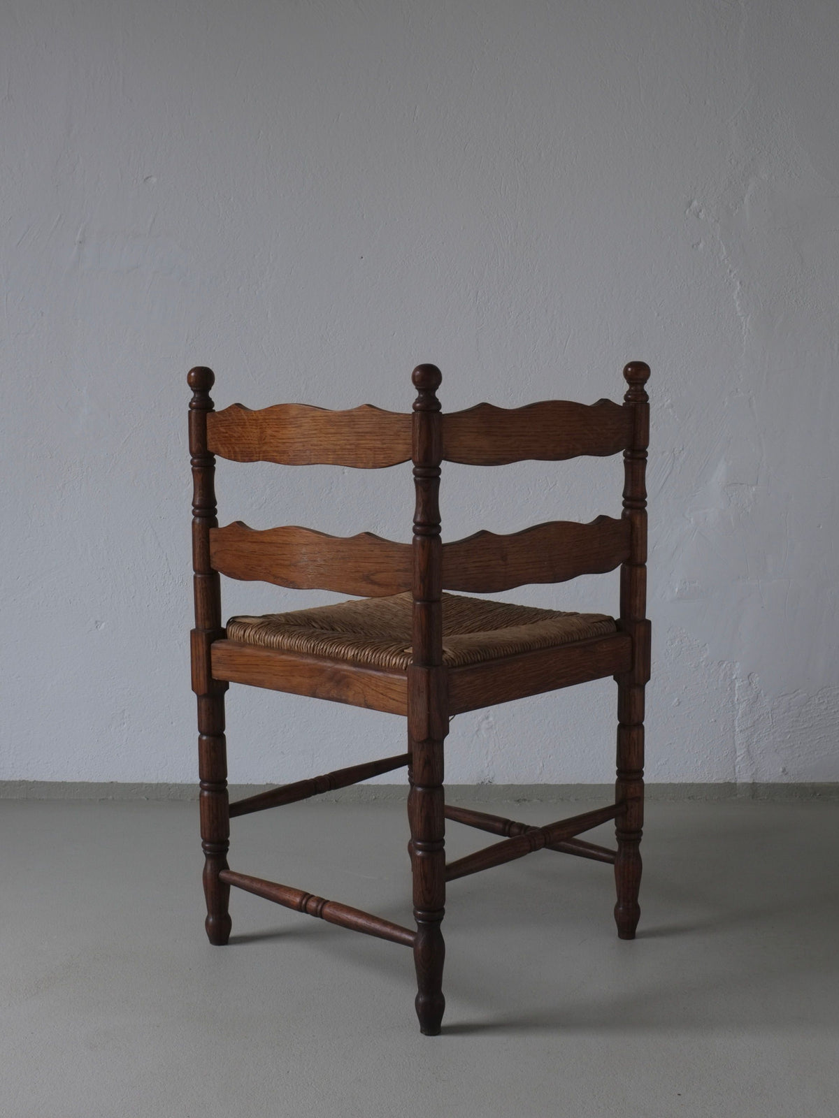 1950s carved oak corner chair with woven rush seat, turned legs