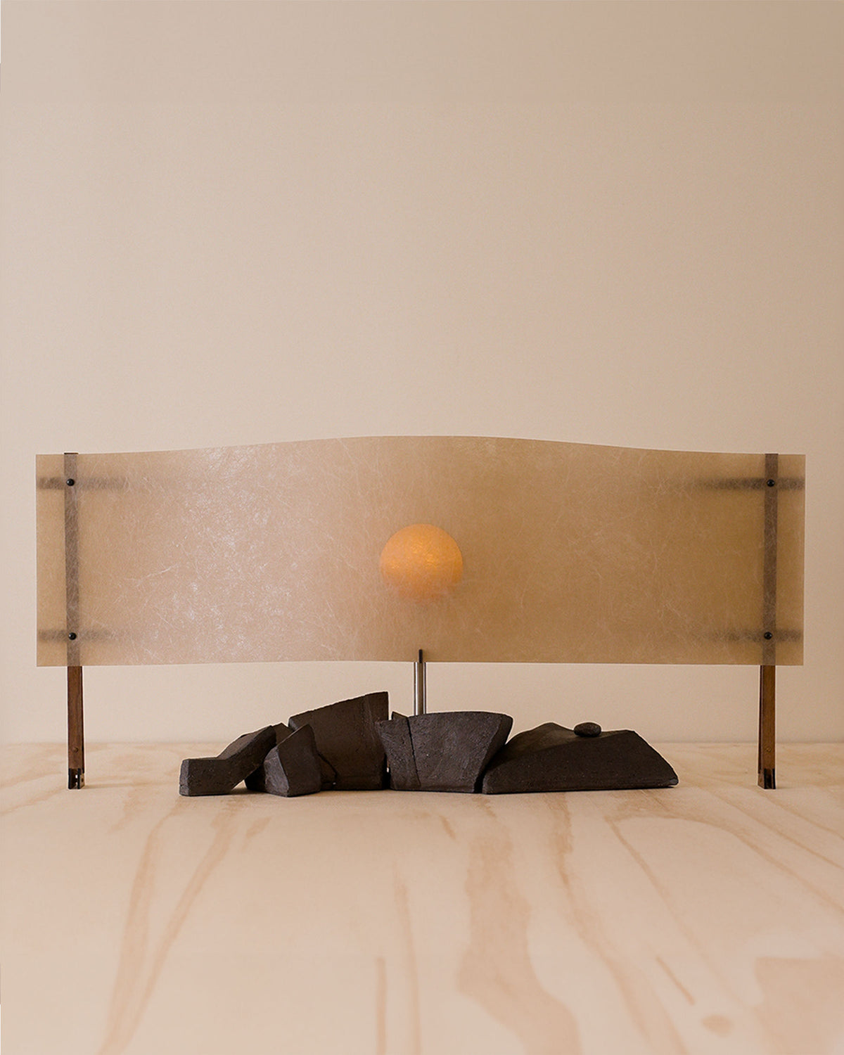 Sunrise table lamp with orange sphere and brass base on marble surface