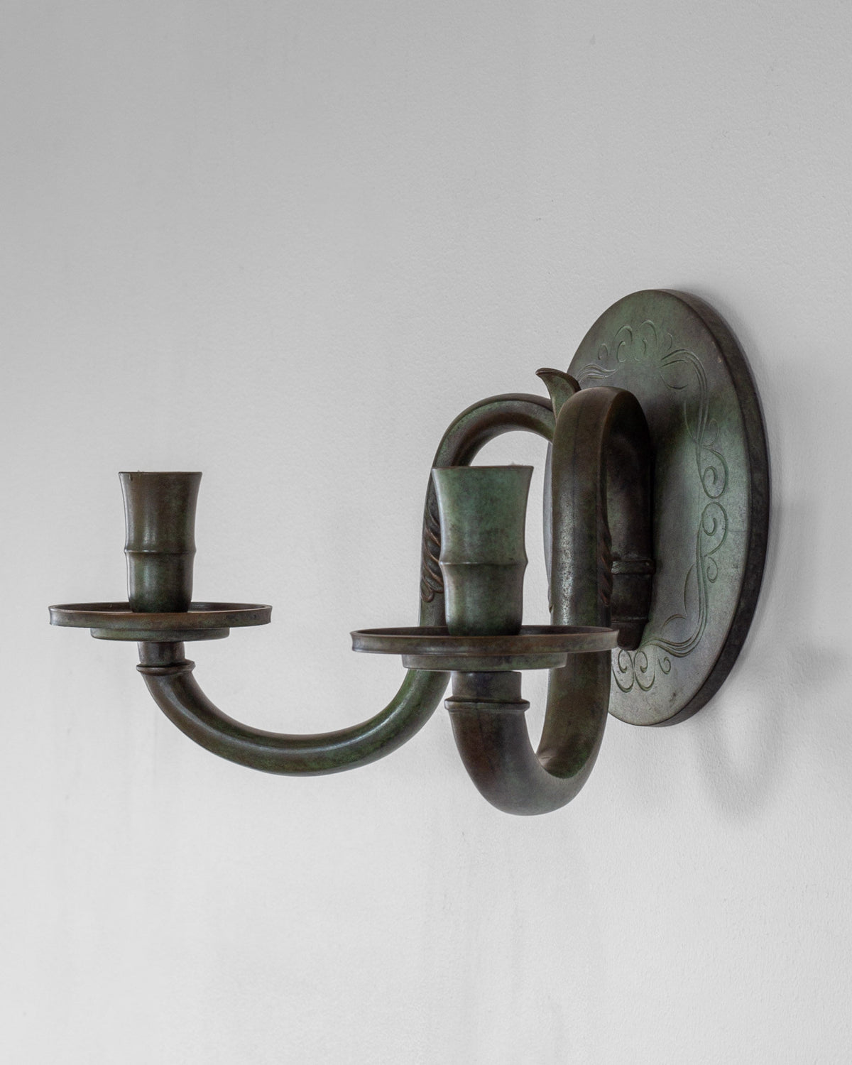 Bronze Art Deco wall sconce with curved arms and decorative backplate