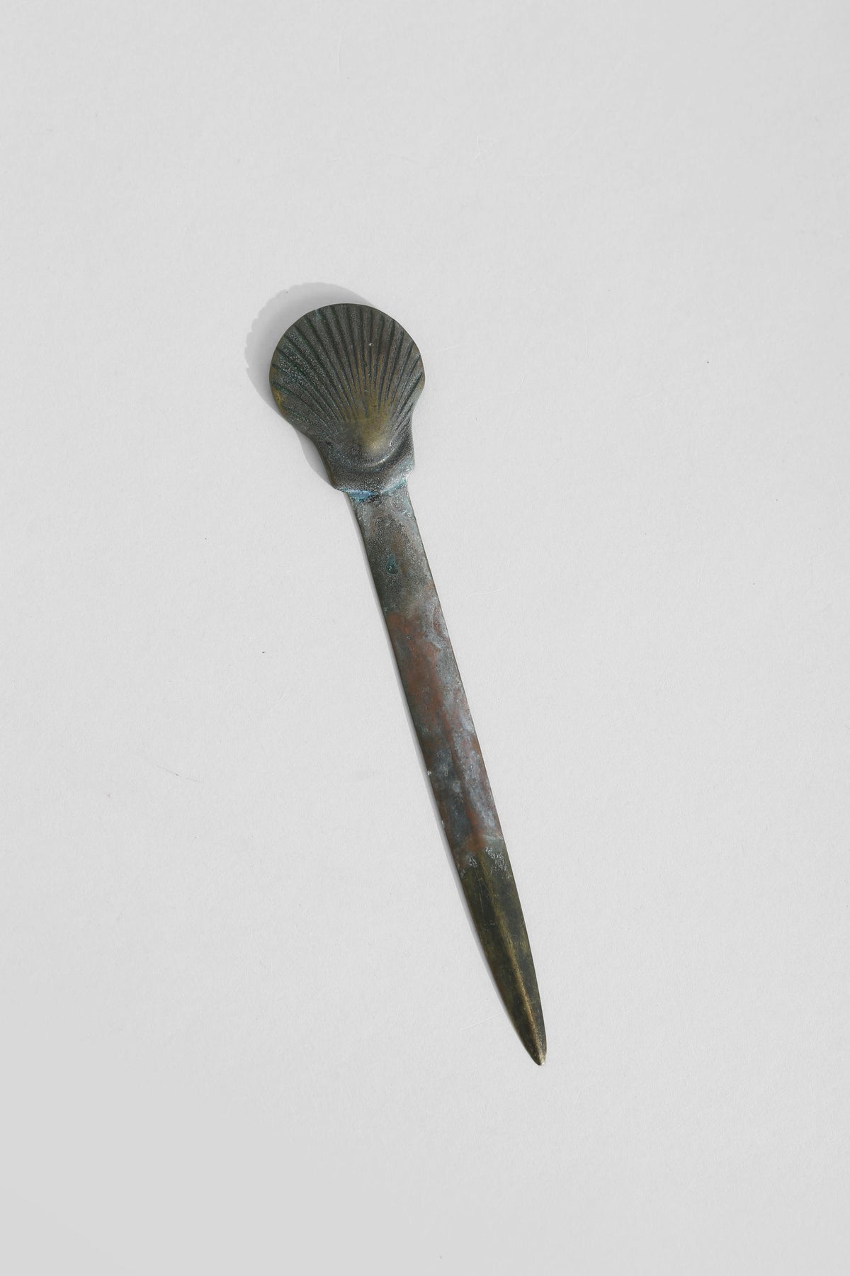 Brass shell letter opener with patina finish showing side profile