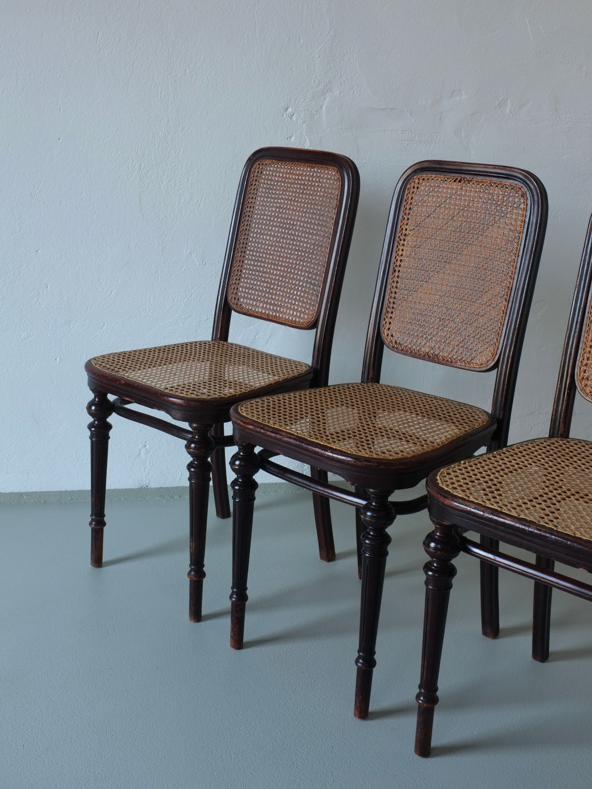 Three Thonet bentwood cane chairs with turned legs detail view