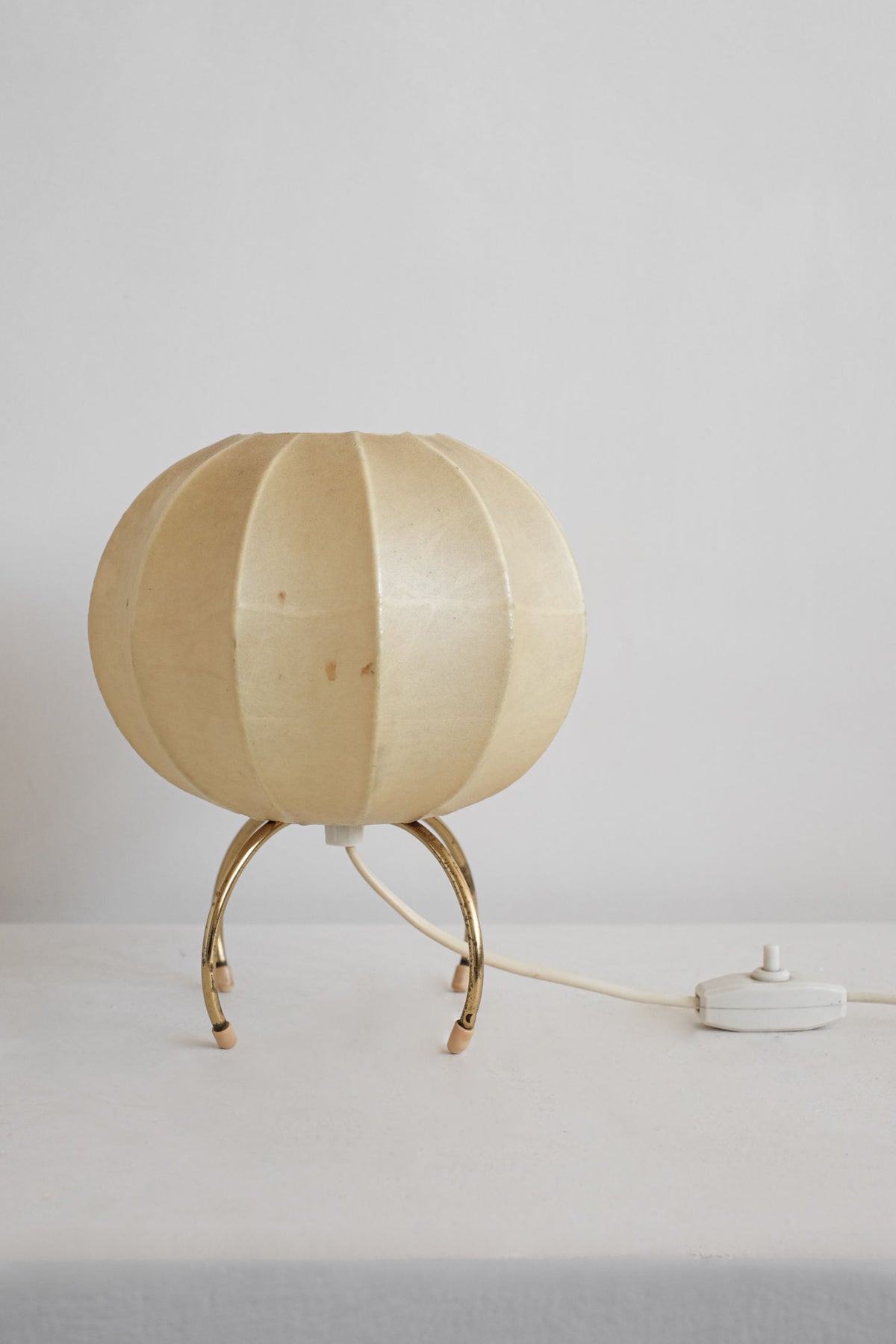 Cocoon table lamp with ribbed cream shade on brass tripod legs