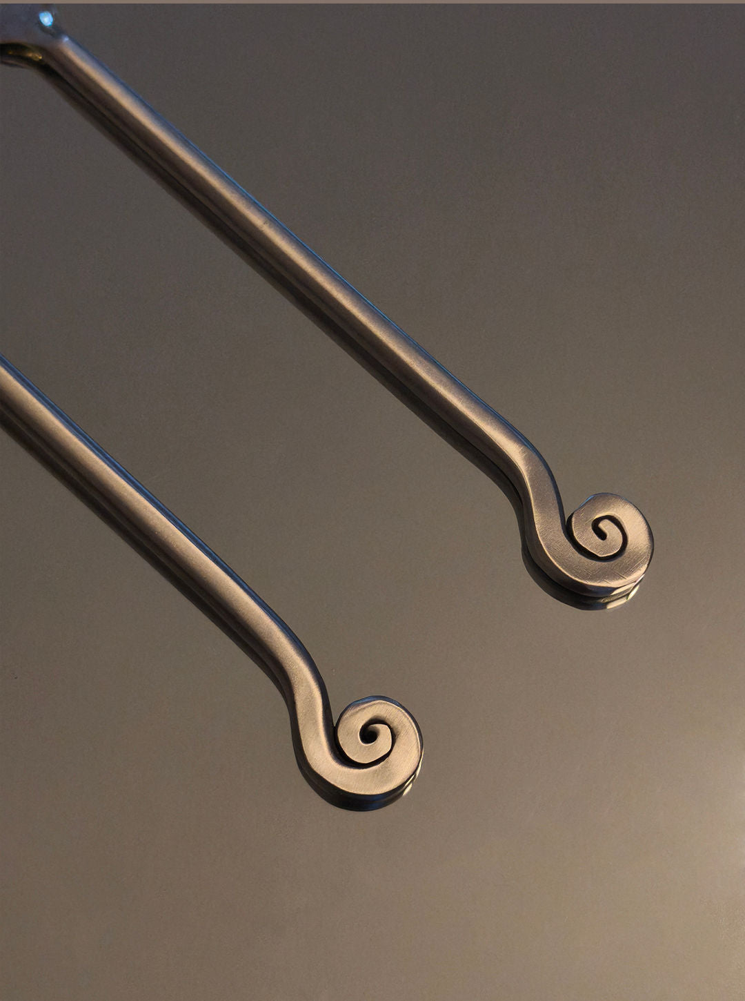 Spiral brass cutlery servers detail showing curved handles