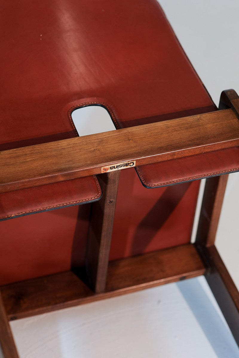 Close-up detail of walnut wood frame and red leather seat of Cassina dining chair