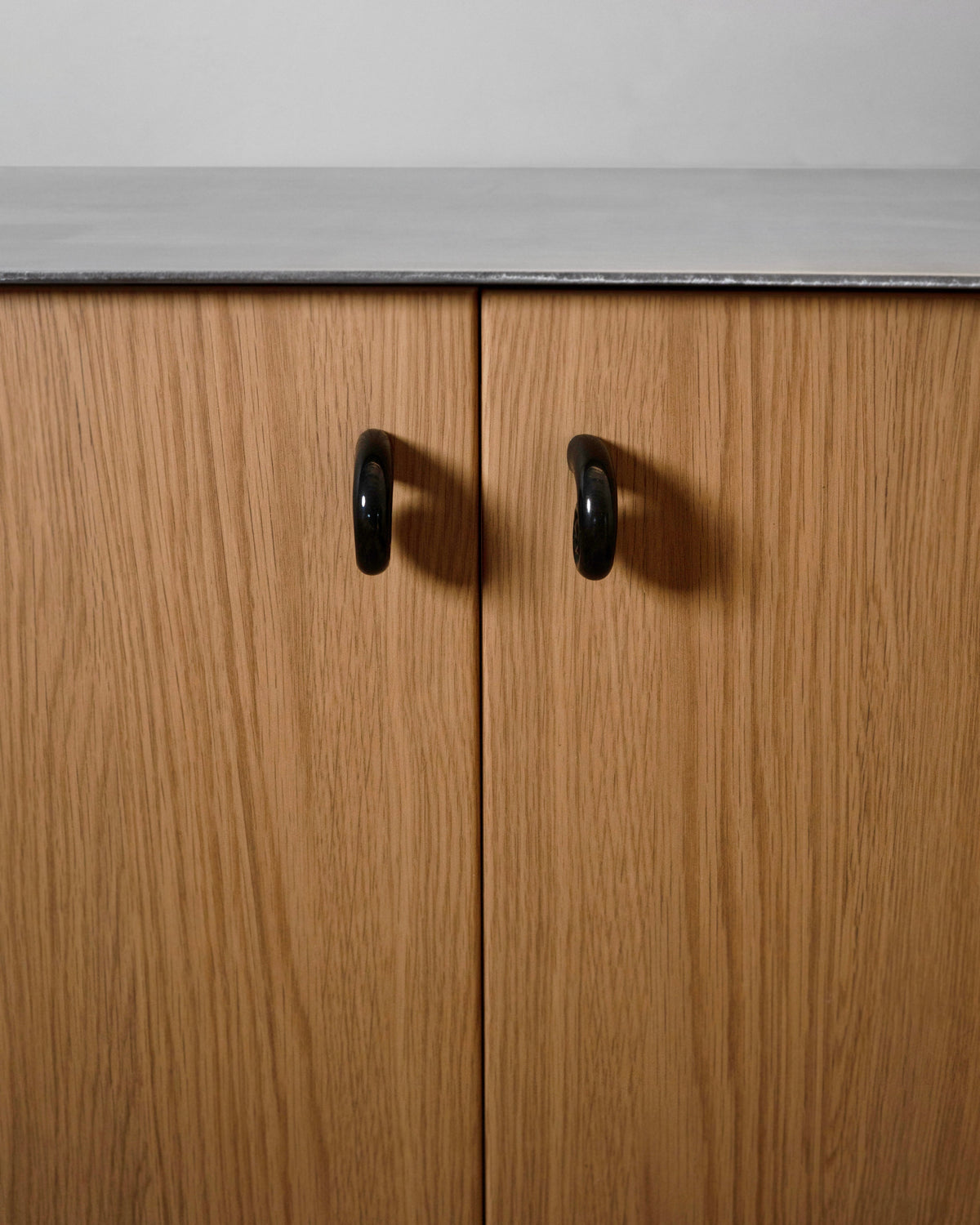 Noelle Knob - Antique Brass — top view on wooden cabinet doors