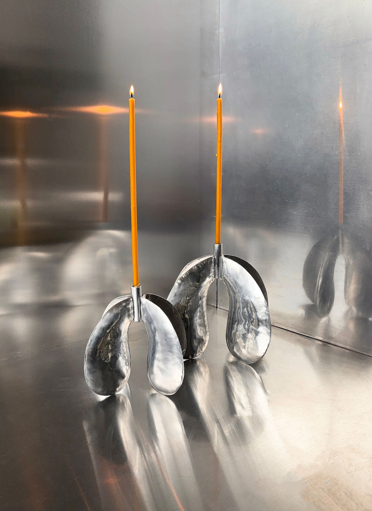 Phaedra Candle Holder Small — angled view on metallic surface with orange candles