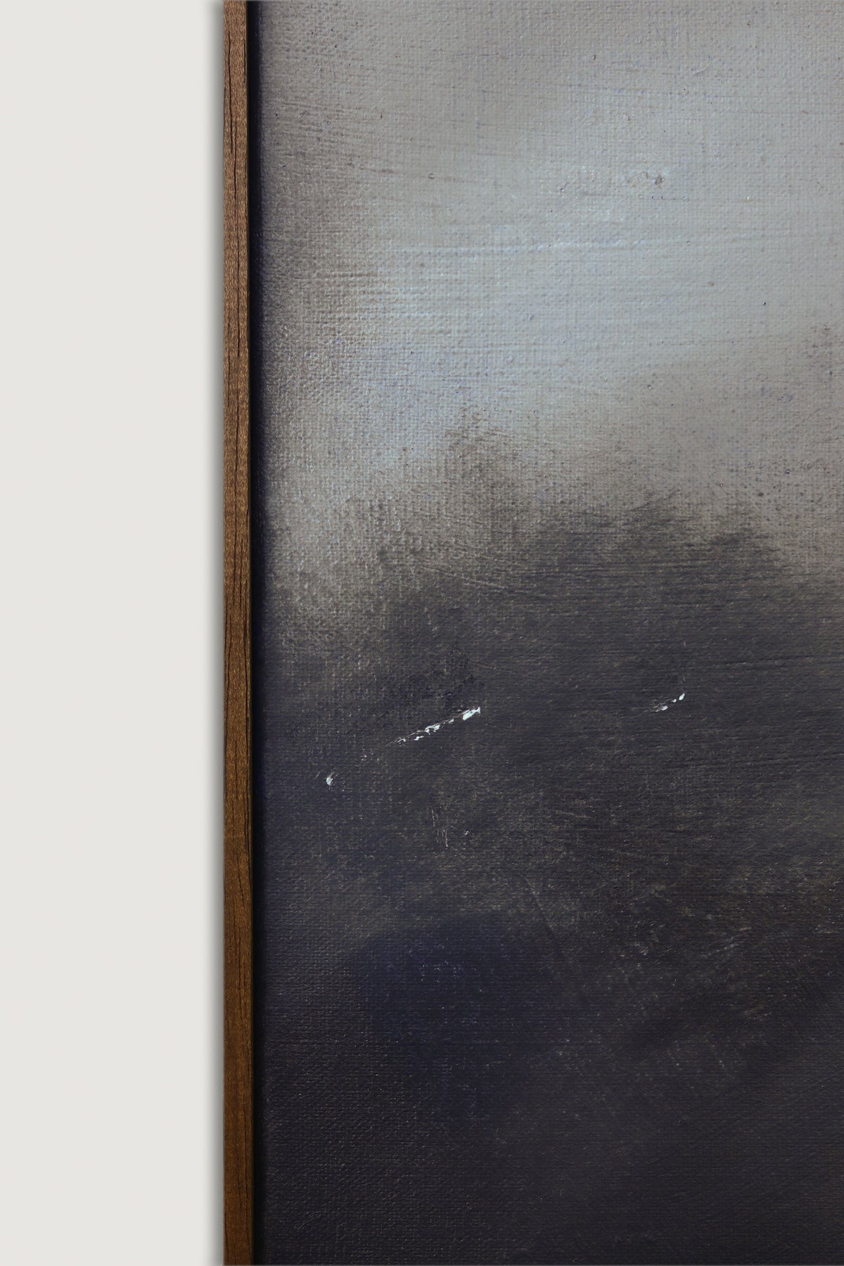 Close-up of "As Night Draws In" by David Hardy—acrylic on linen with dark, moody brushstrokes in black, gray, and blue. Two small white marks near the center and a thin dark wood frame along the left edge.