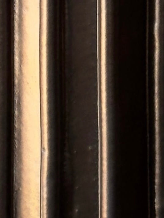 Close-up of vertical metallic bars from Devin Wilde’s Vessel No. IV, with varying light and shadow creating a striped pattern.
