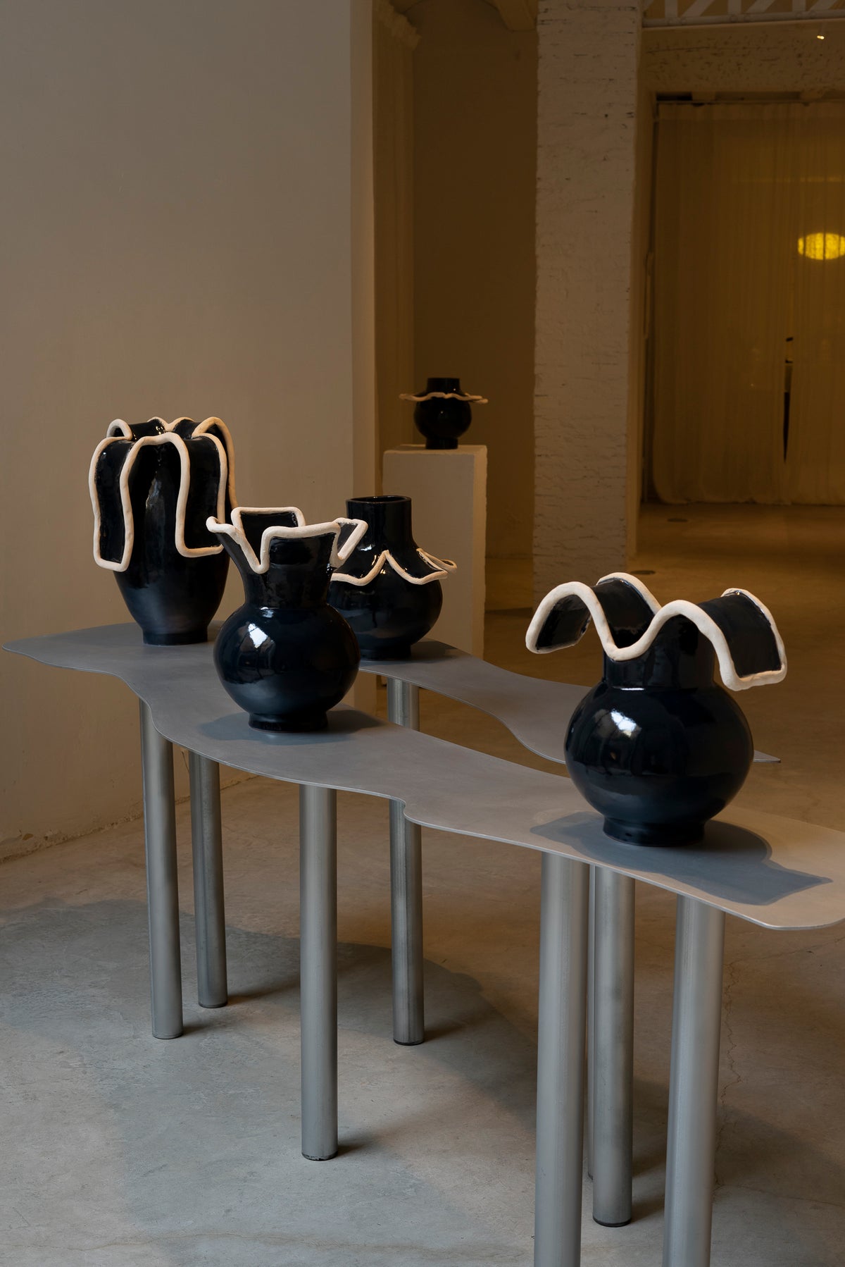 Navy blue ceramic vases with wavy white rims, gallery display