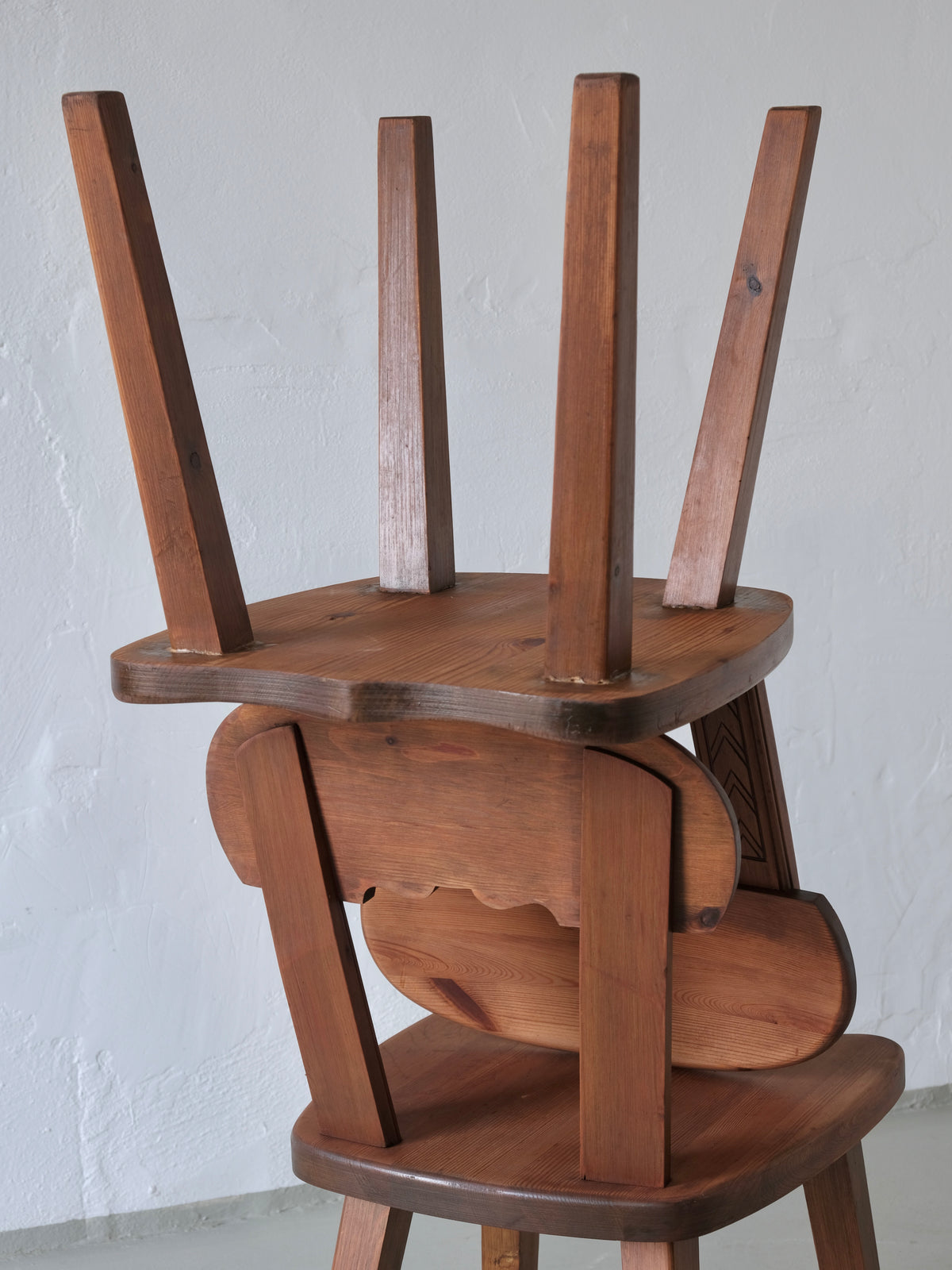 Stacked rustic Swedish pine chairs showing carved details