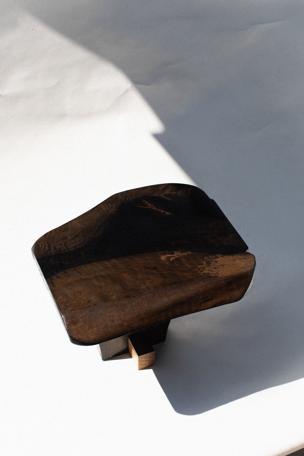 Qawha walnut side table detail showing curved wood surface