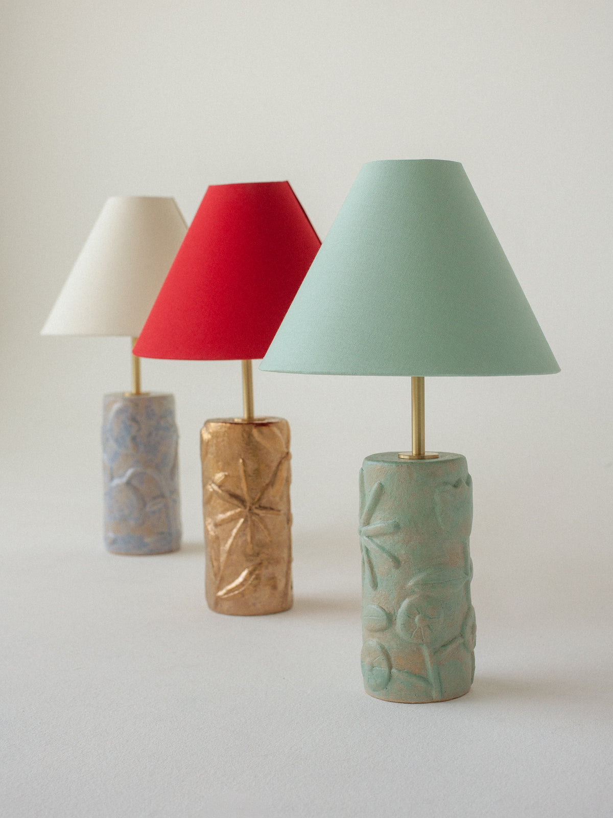 Three ceramic table lamps with textured bases and colorful shades