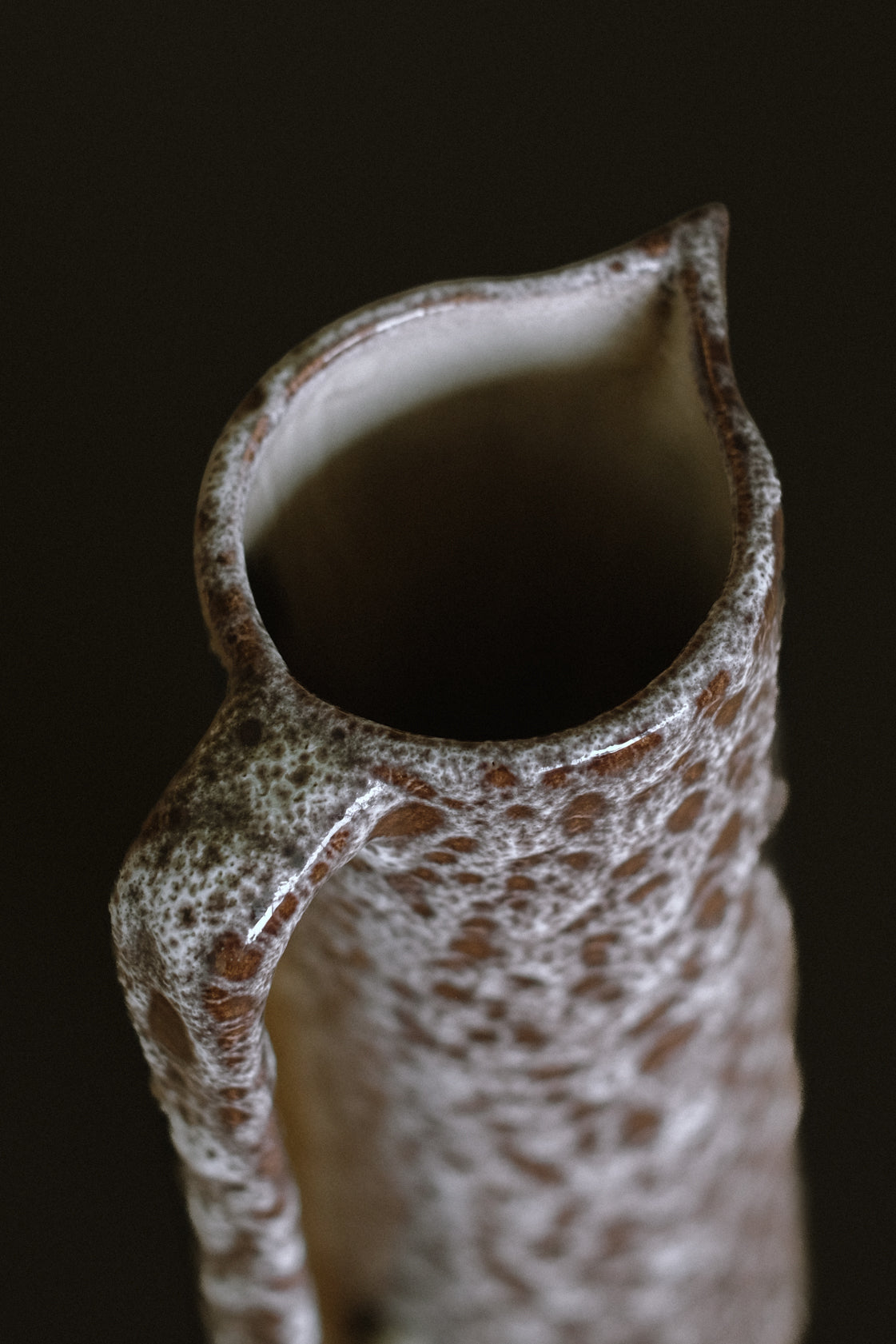 Close-up detail of handmade stoneware pitcher spout and rim
