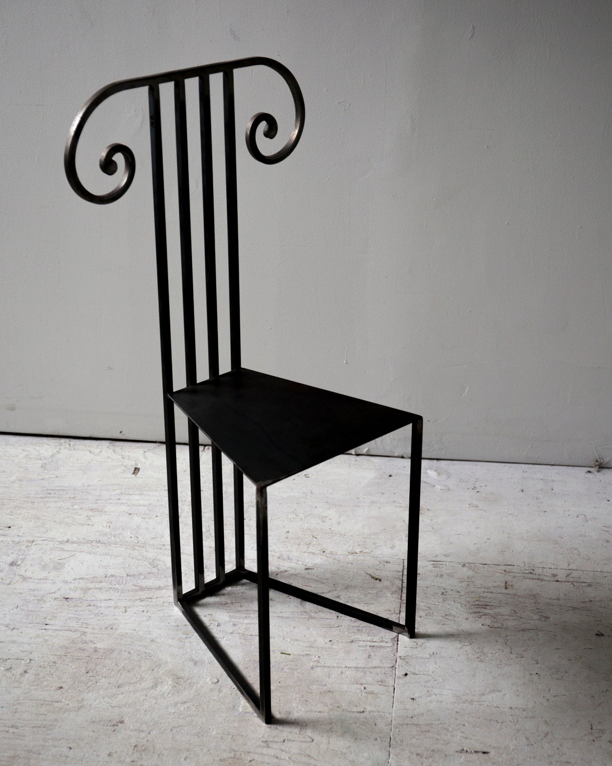 Black metal Column Chair with vertical slat back and curved scrolls