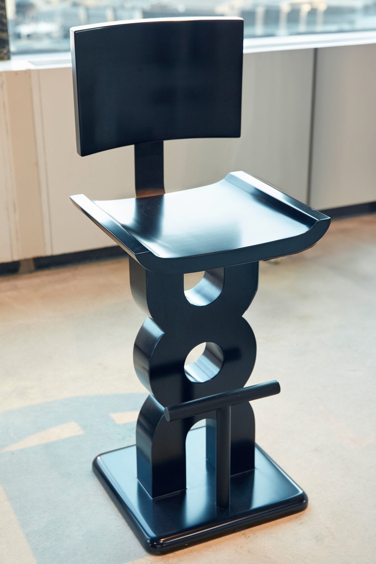 Soro Bar Stool — angled view showing black lacquer finish in modern setting