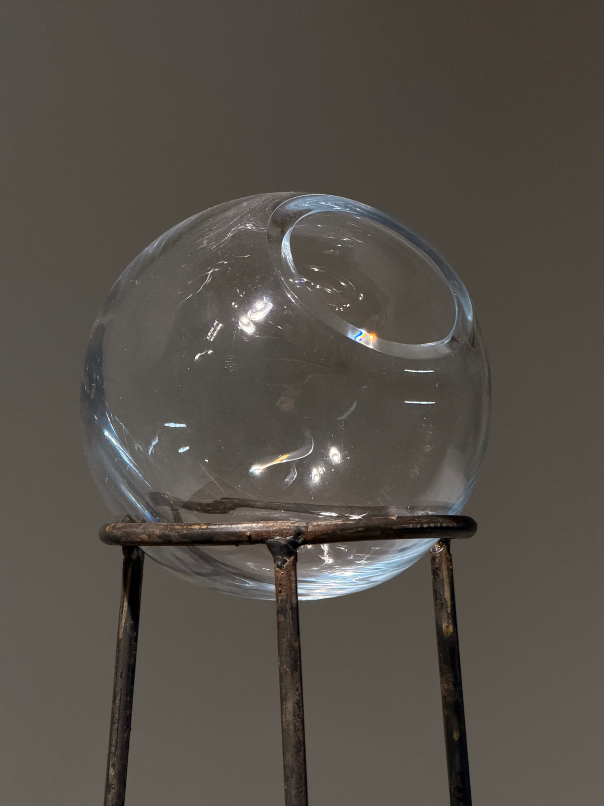Glass orb vase on wrought iron tripod stand, France, circa 1960 — side angle