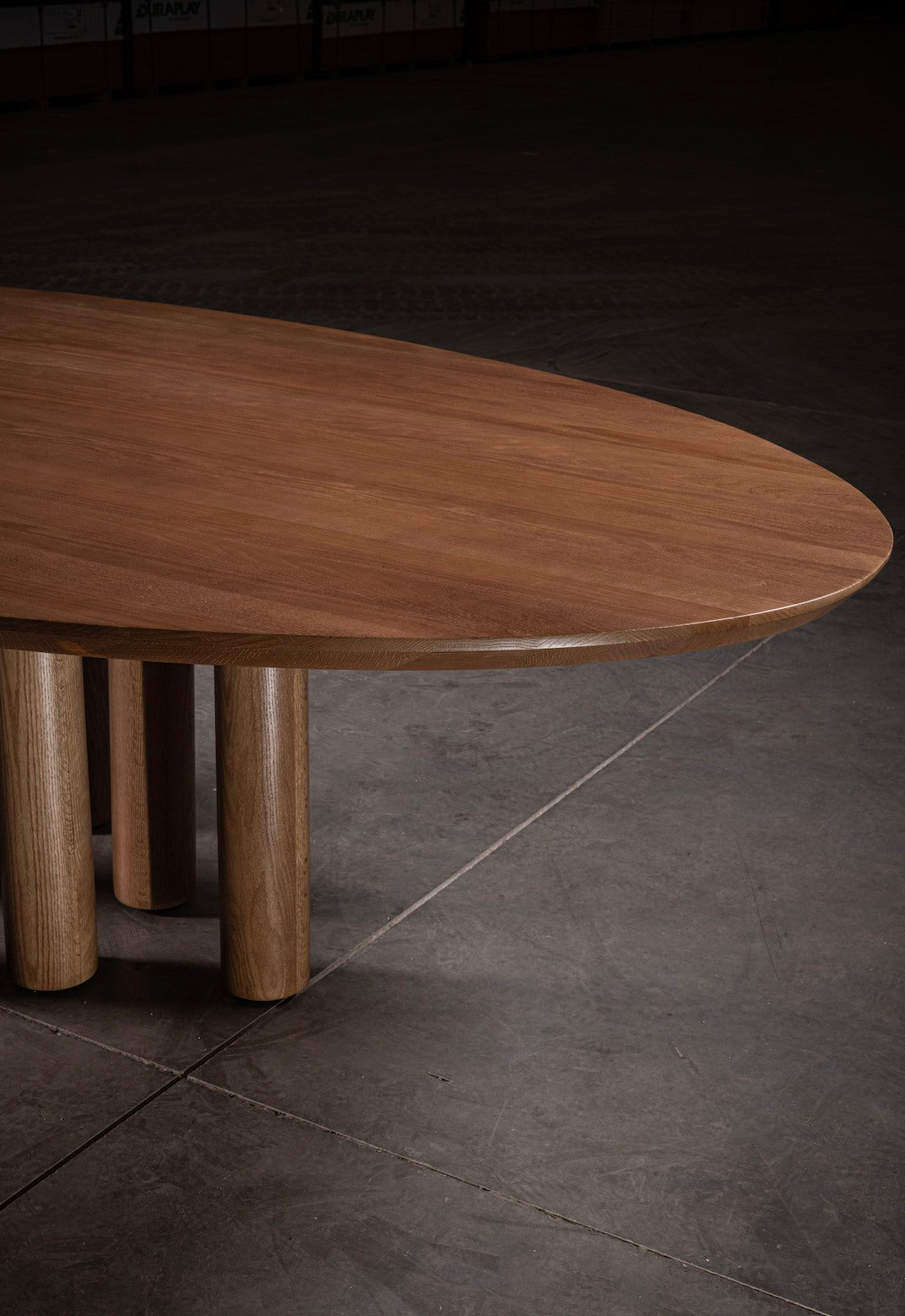 Round walnut dining table with cylindrical oak legs detail