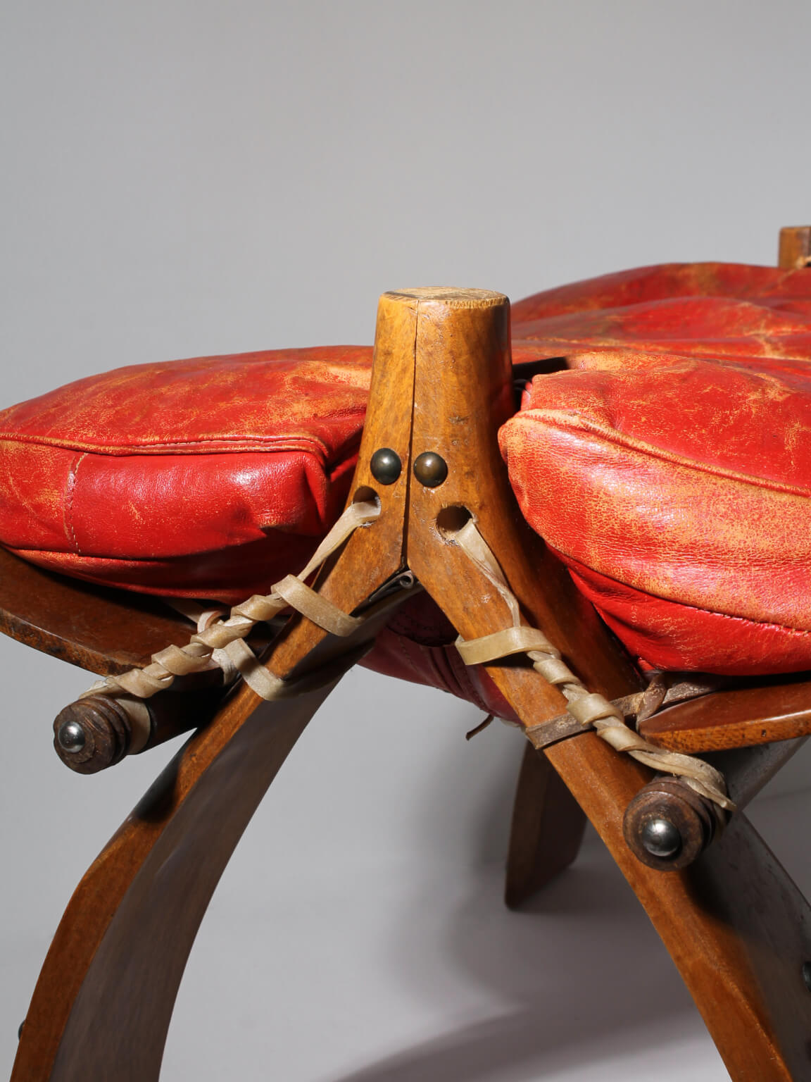 Egyptian Ottoman Camel Saddle Stool — close-up of red leather cushion and wooden frame