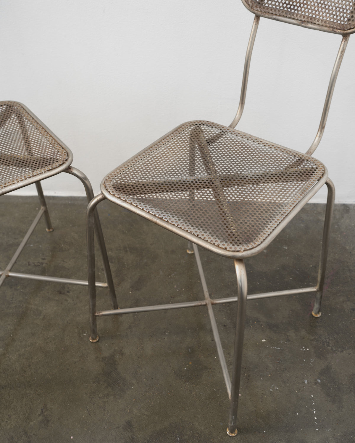 Perforated metal seat detail of vintage dining chairs with tubular legs