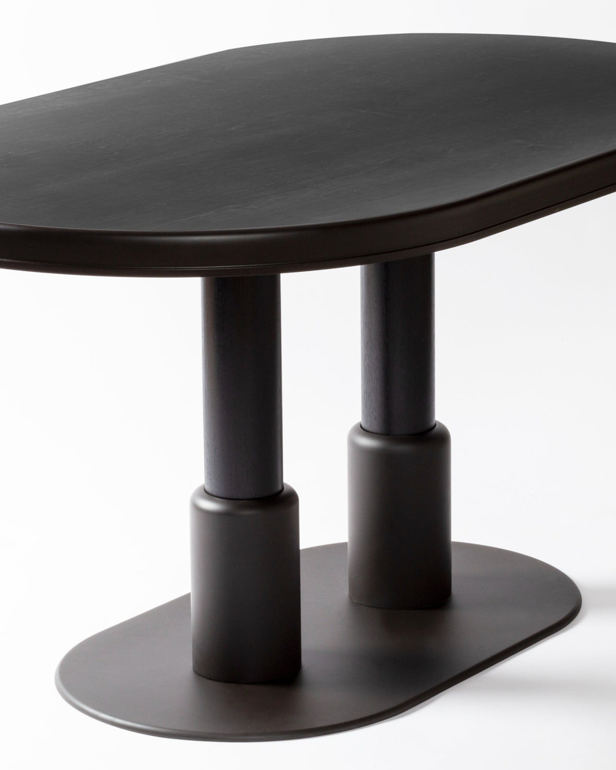 Close-up detail of black oval table base with dual cylindrical supports