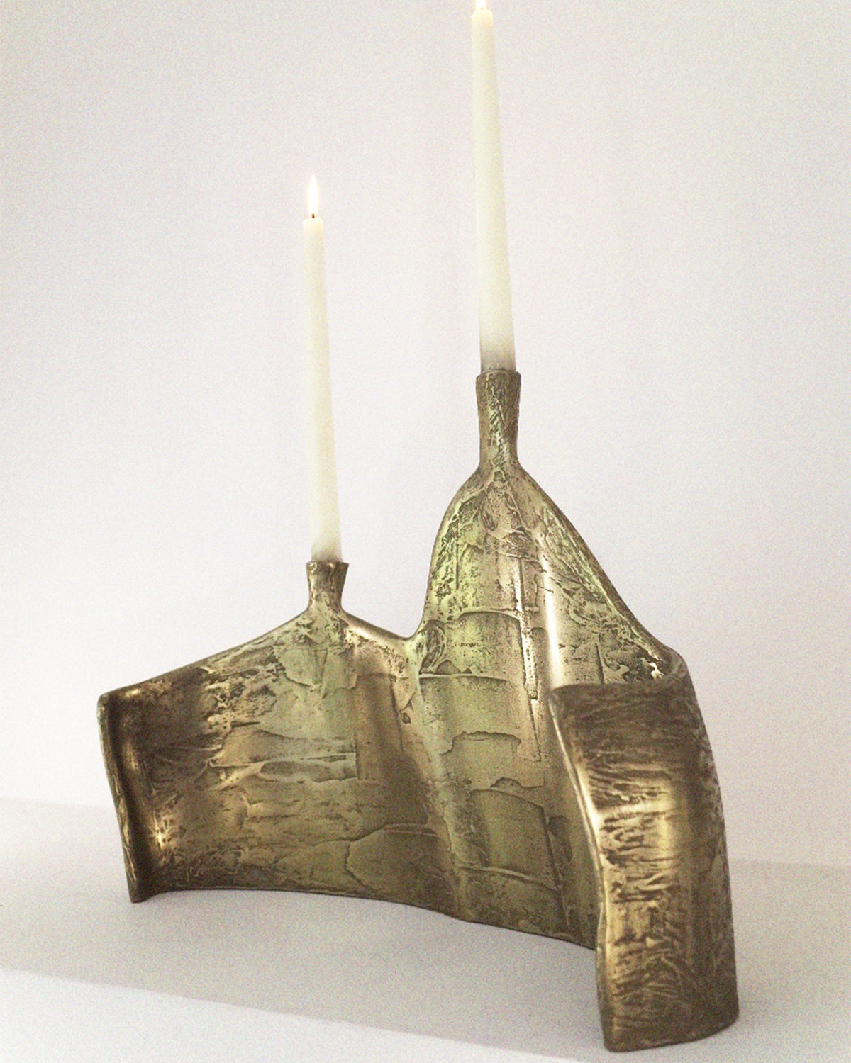Bronze double candelabrum with textured finish and lit candles