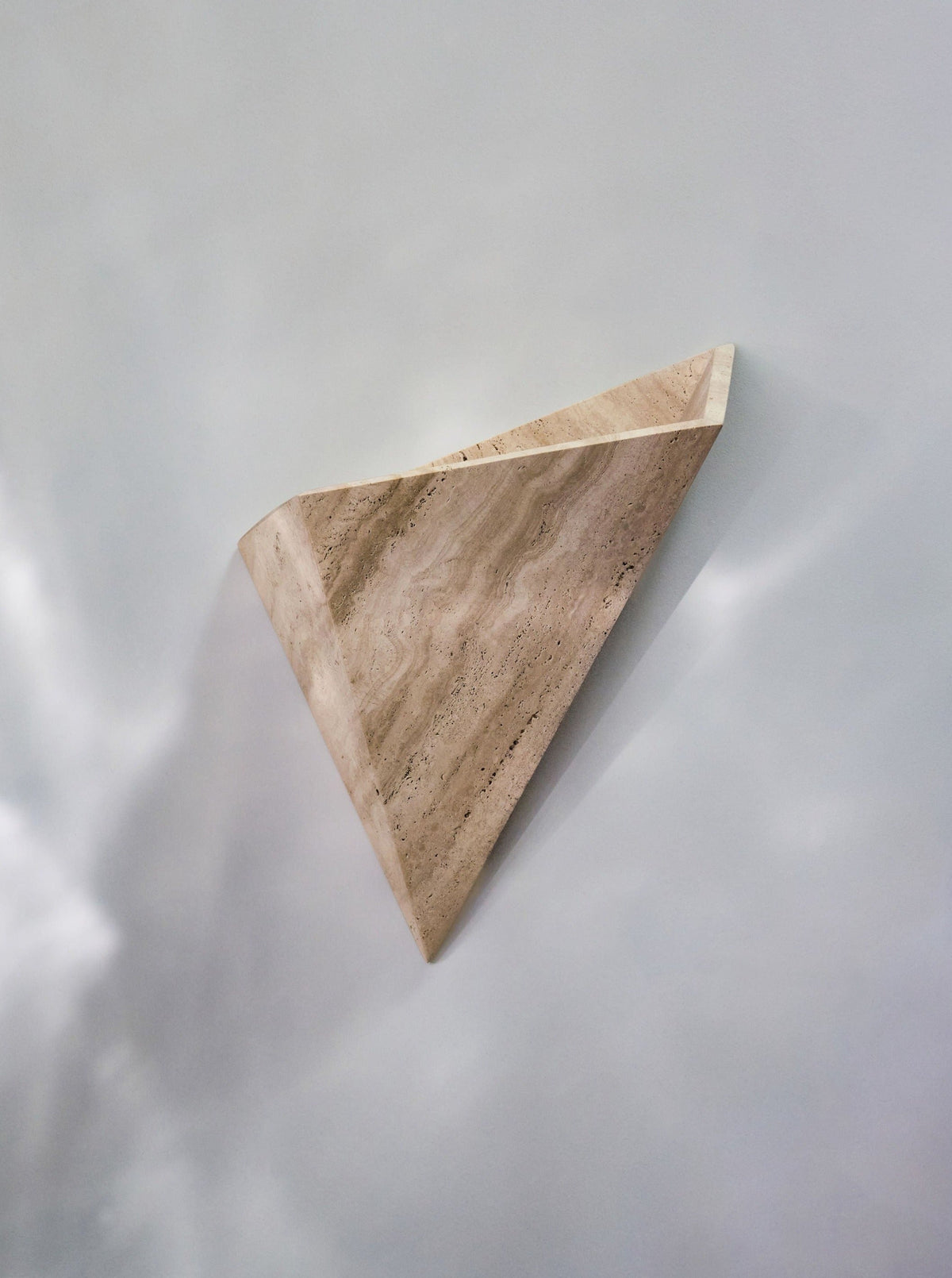 Prehistoric Travertine Wall Light — angled view against light wall