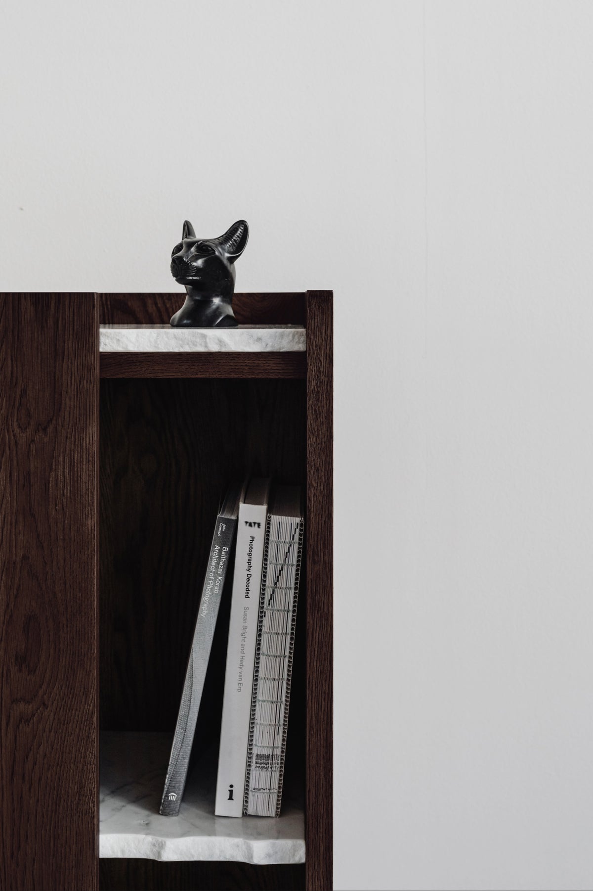 PAVO cabinet detail with black decorative cat figurine on dark wood shelf