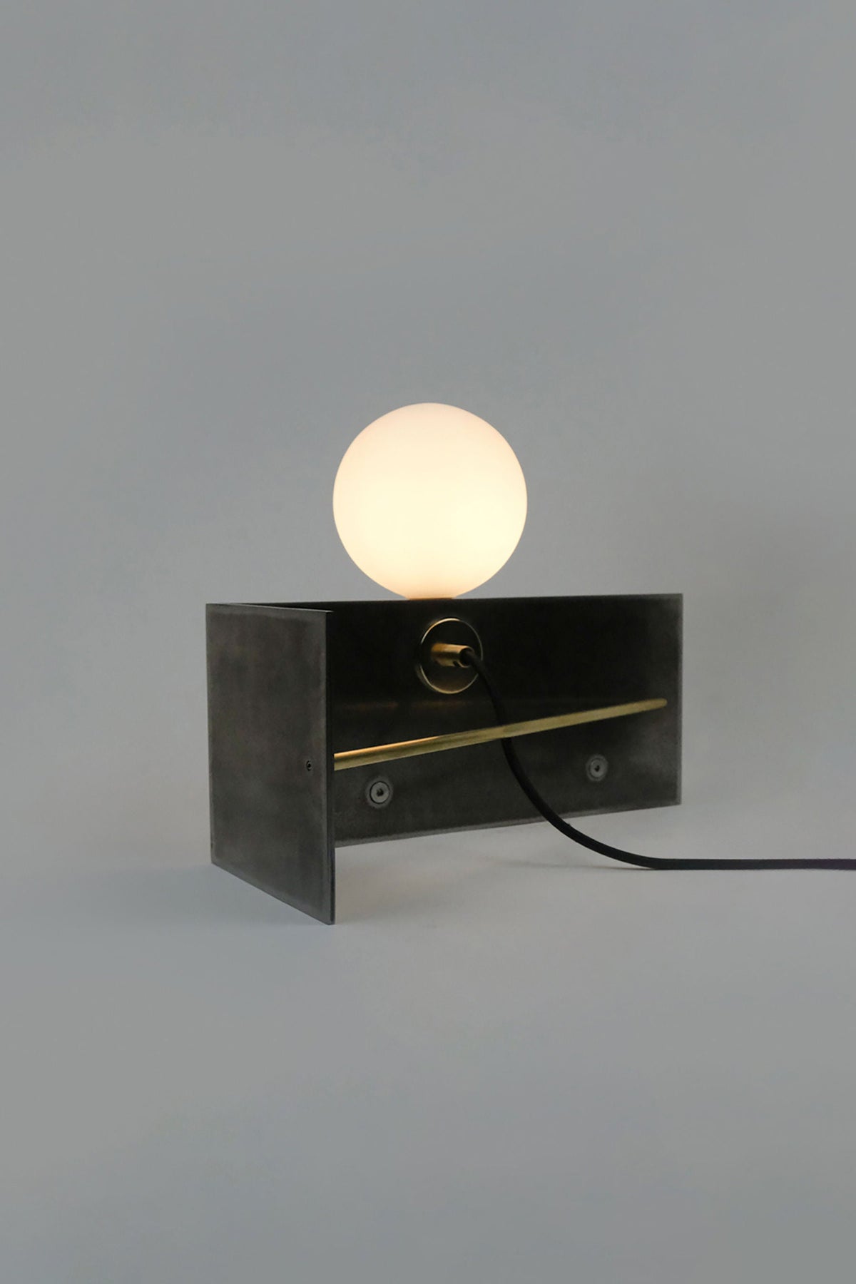 Modern black metal table lamp with glowing spherical bulb on top