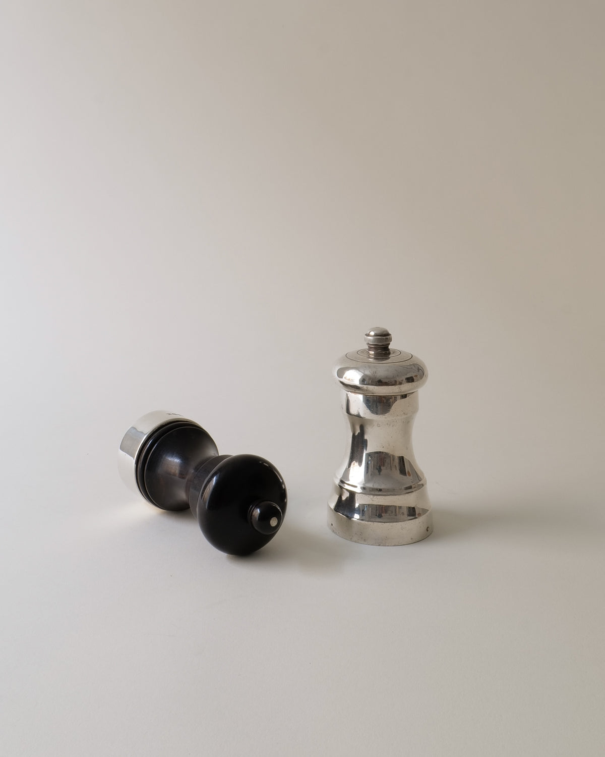 Silver pepper mill standing beside disassembled black salt grinder