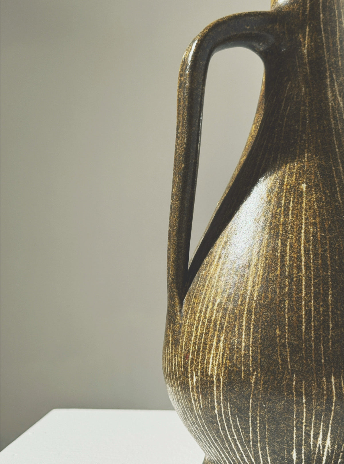 Golden ceramic pitcher handle detail showing textured ribbed surface