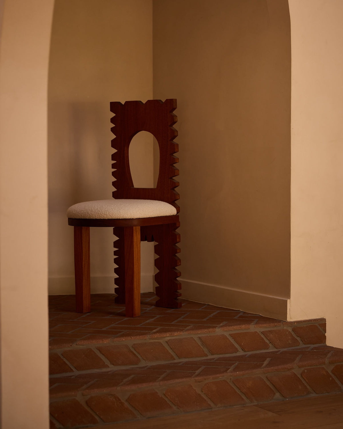 Jura dining chair with sculptural dark wood back in corner niche