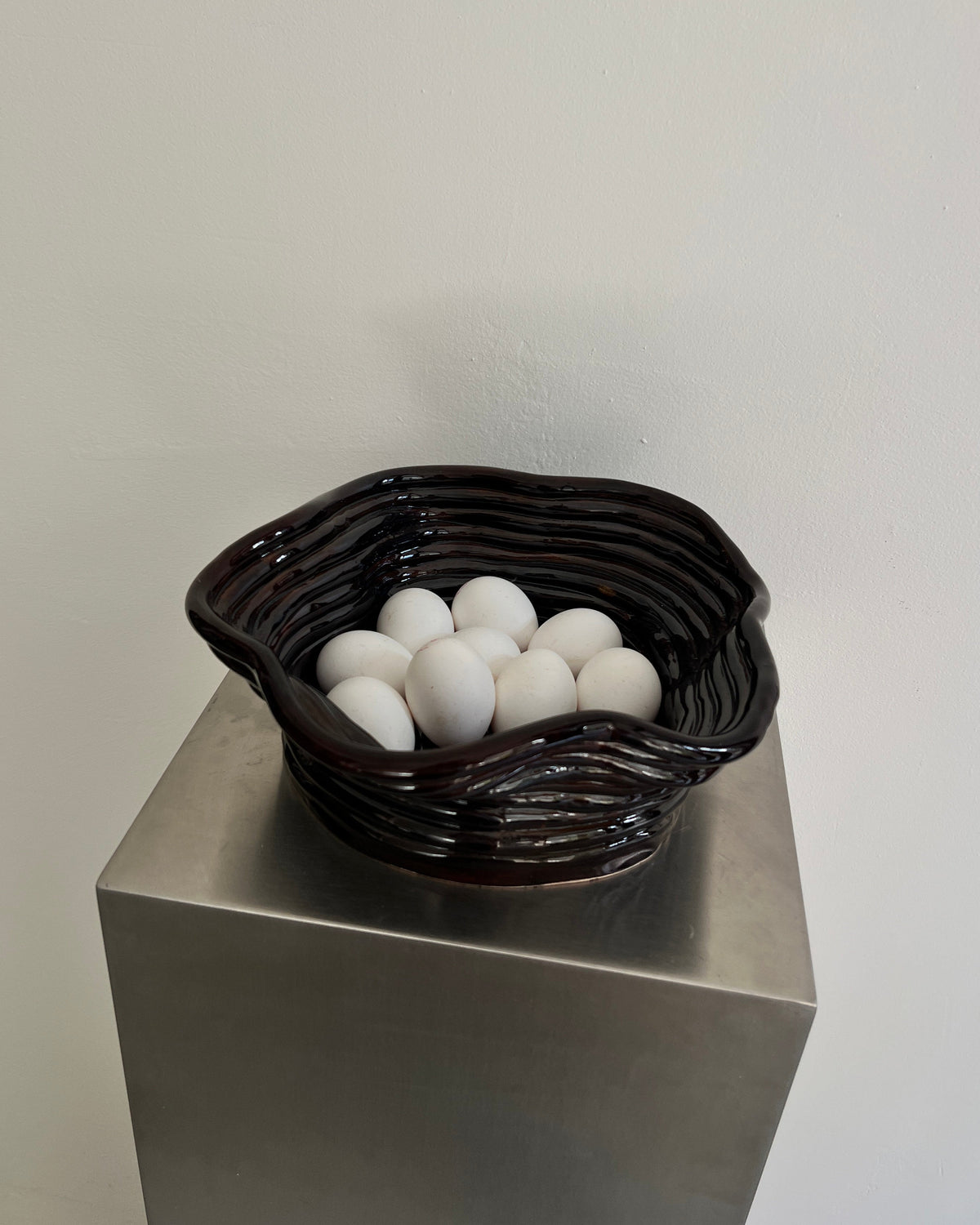 Chocolate gloss ceramic bowl with white eggs on pedestal display