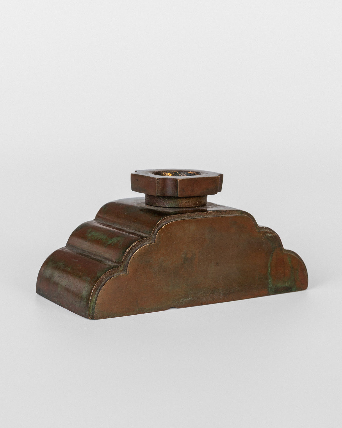 Bronze candleholder base detail showing patinated stepped form
