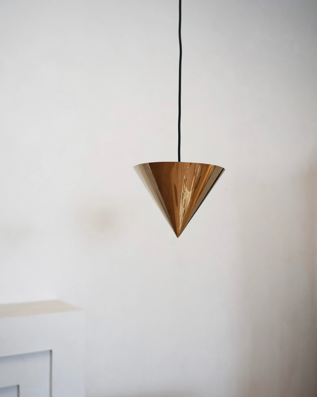 October Ceiling Lamp - Polished Brass — hanging in minimalist interior setting