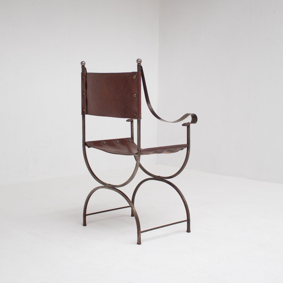 French pair of Iron Curule Chairs in Leather — angled view on white backdrop