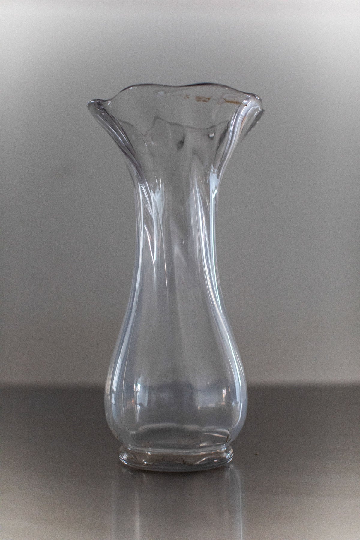 Glass Vase — clear glass with flared top on metal surface