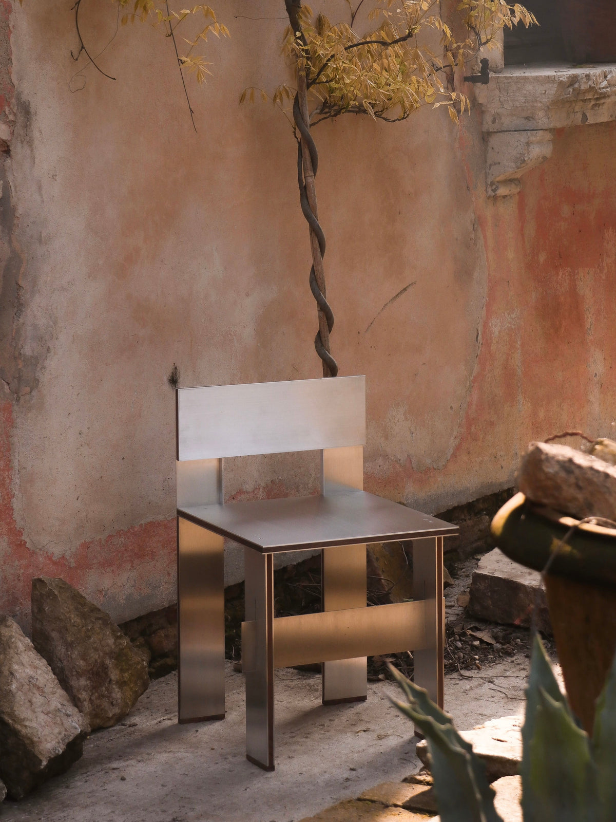 Sandwich Chair — side angle showing stainless steel construction in outdoor setting