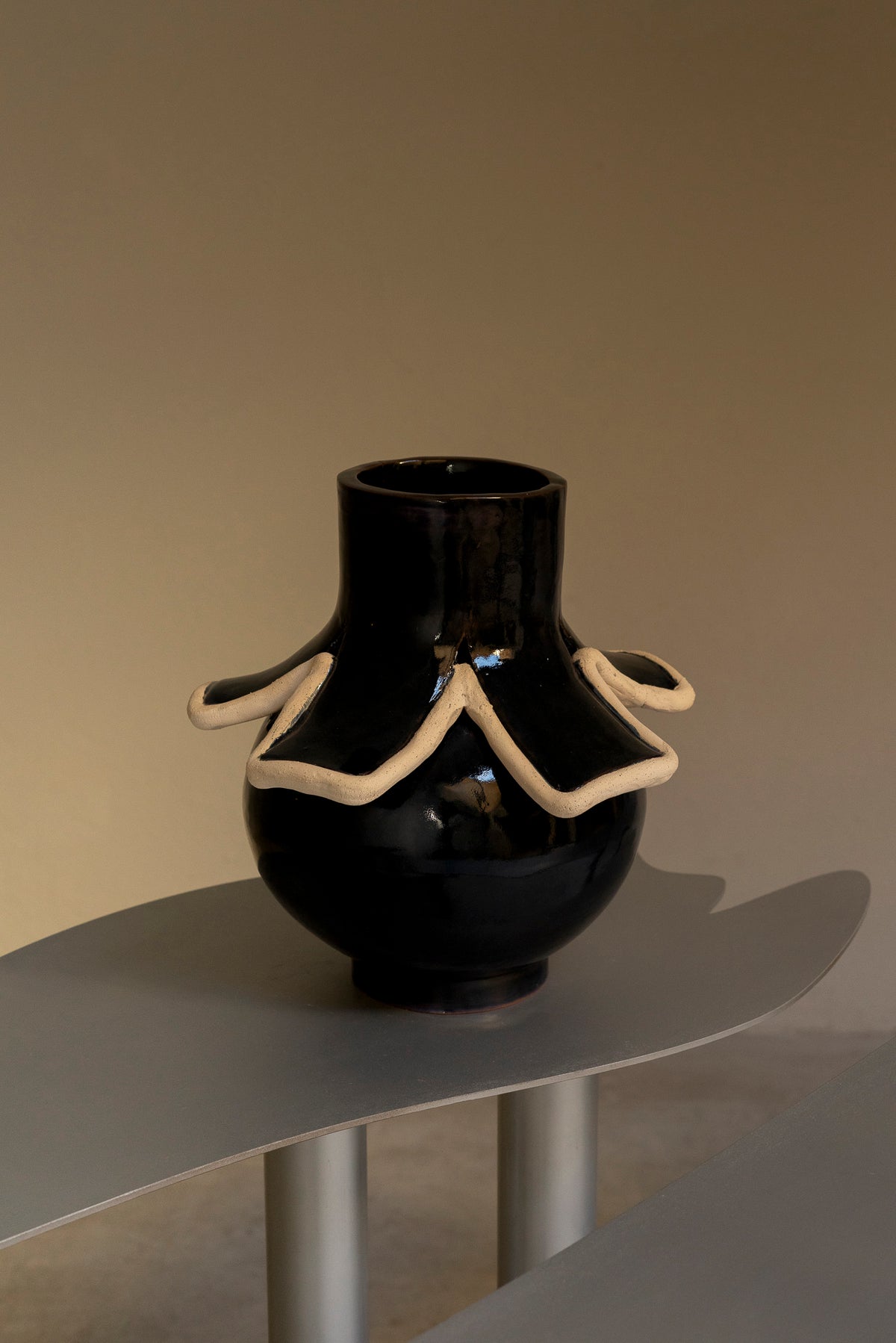 Glossy black ceramic vase with cream clay serpentine detail, front view