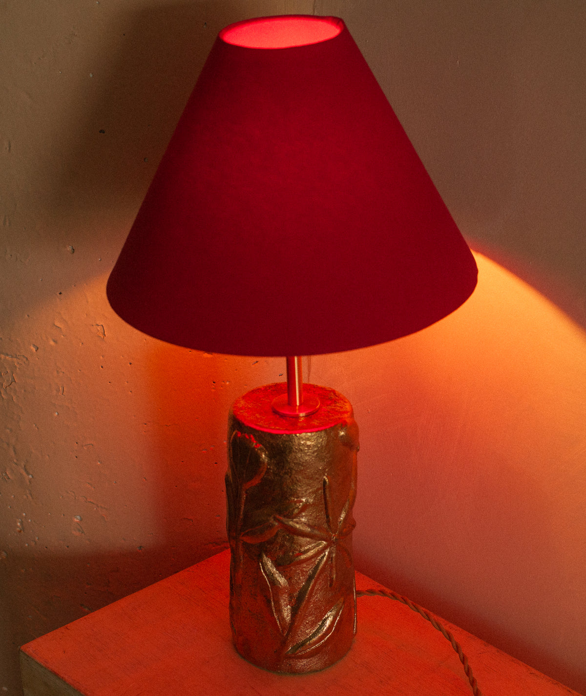 Red-lit Folklore gold table lamp with textured cylindrical base