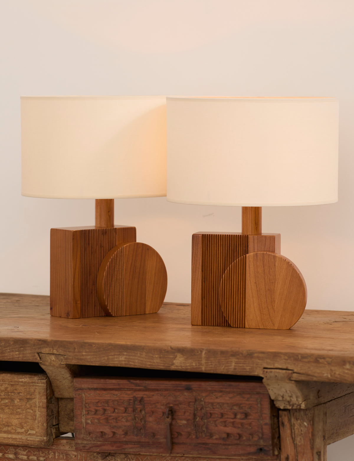 Set of 2 Vintage Artisanal Table Lamps In Solid Wood From France c. 1970 — angled view on rustic wooden table