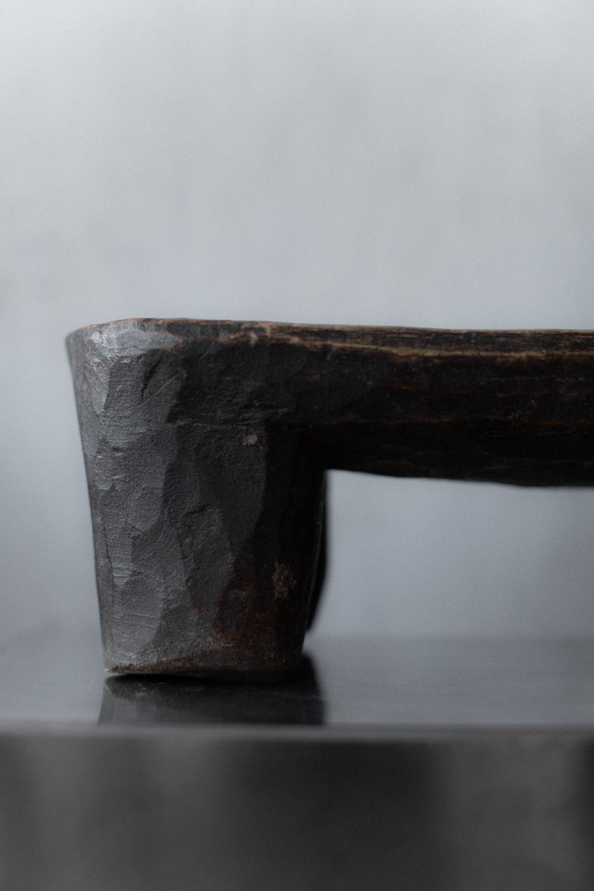 Senufo Stool — side angle showing textured dark wood finish