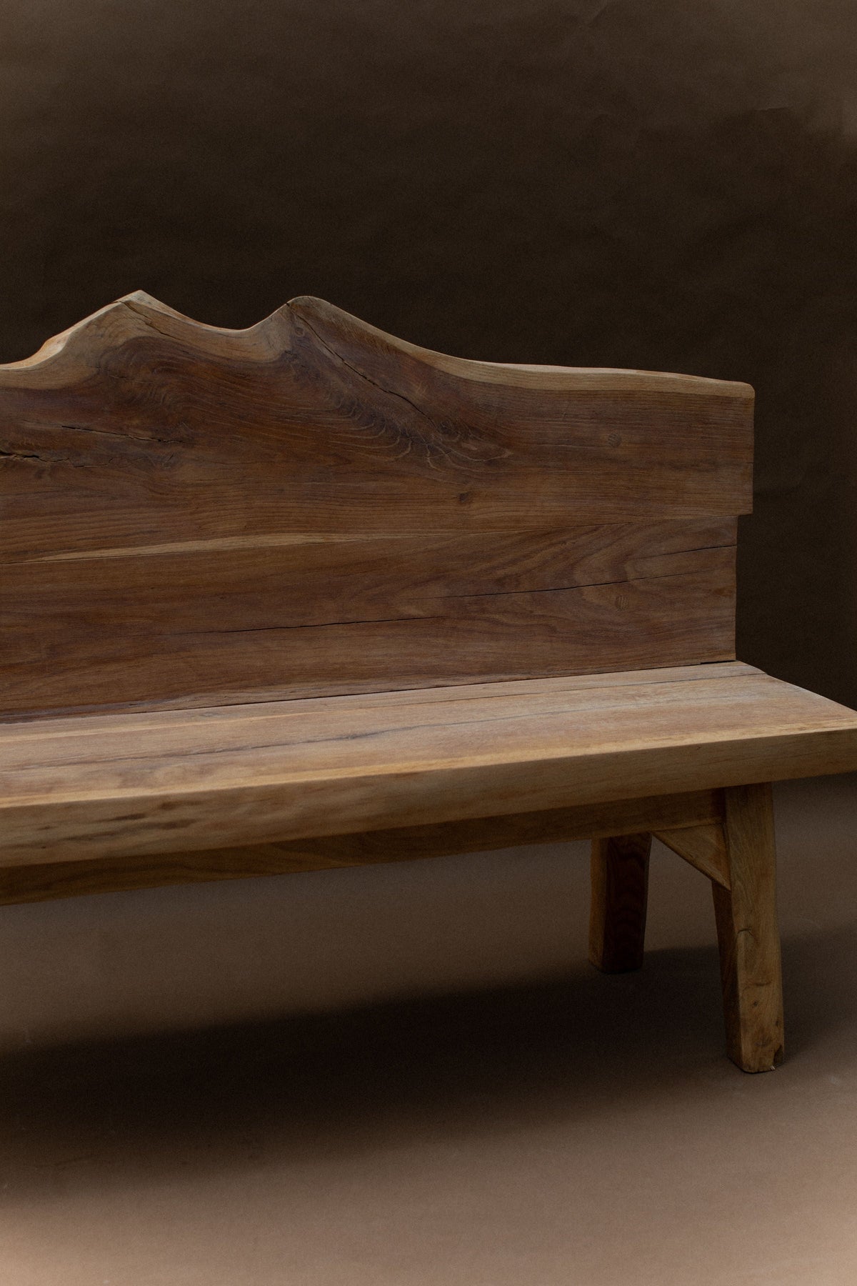 Brutalist solid wood bench with curved backrest detail