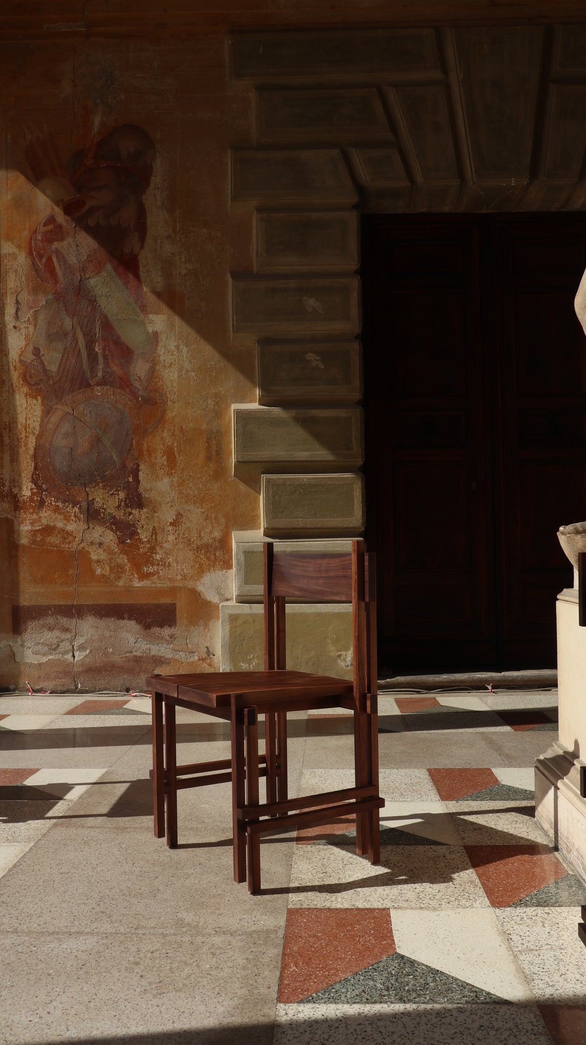 Modern walnut stack chair by Filippo Andrighetto in historic setting