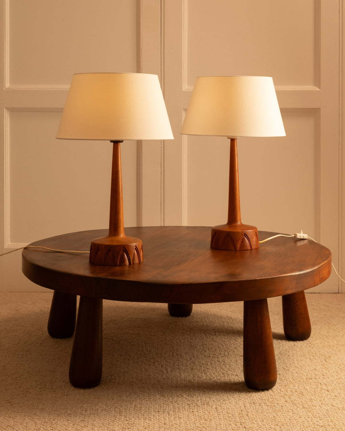Two Swedish wooden table lamps with cream shades on round coffee table