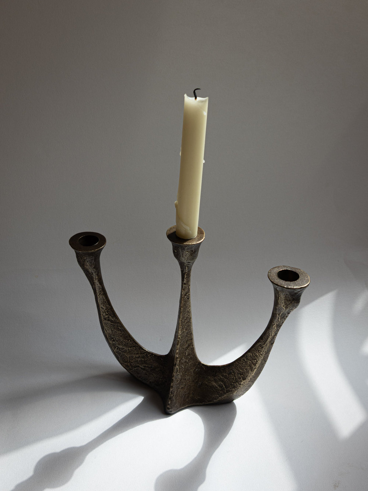 Three-arm brutalist bronze candelabra, Germany 1970s, one cream taper candle